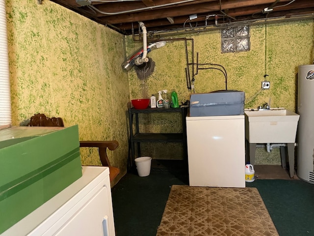 laundry area with water heater, washing machine and clothes dryer, a sink, and laundry area