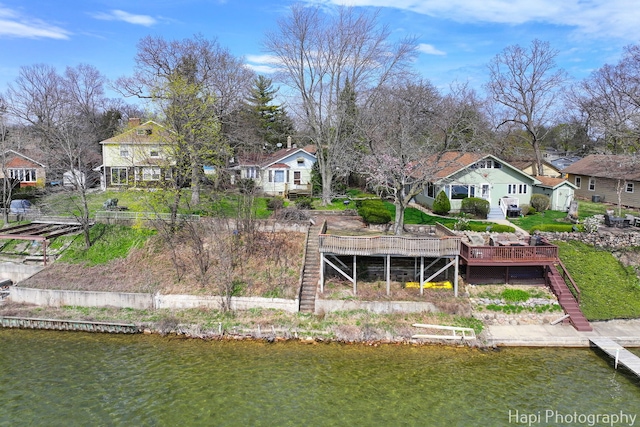 back of house featuring an outdoor structure, a residential view, and a deck with water view