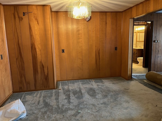 unfurnished dining area with wooden walls, carpet flooring, and a chandelier