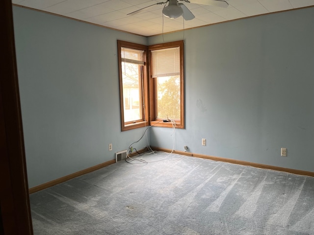 spare room featuring baseboards, a ceiling fan, visible vents, and carpet