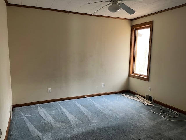 carpeted spare room with a ceiling fan, baseboards, ornamental molding, and visible vents