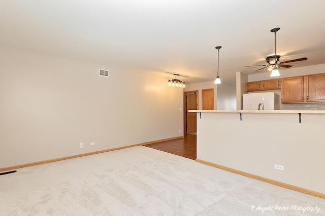 unfurnished living room with ceiling fan, baseboards, visible vents, and carpet
