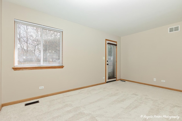 carpeted empty room featuring baseboards and visible vents