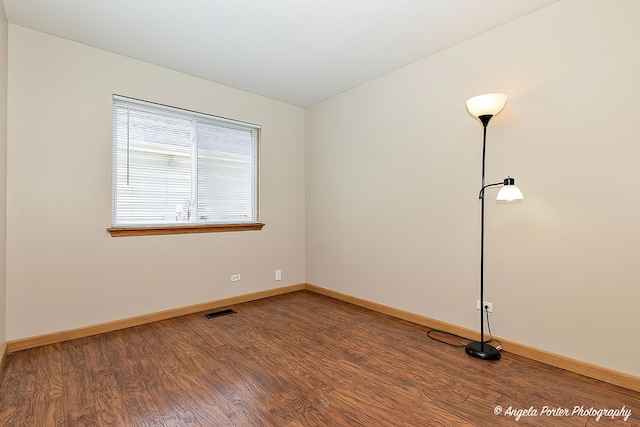 empty room with baseboards, wood finished floors, and visible vents
