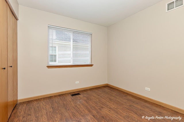 unfurnished bedroom with baseboards, wood finished floors, visible vents, and a closet