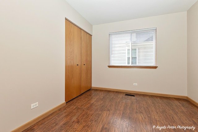 unfurnished bedroom featuring visible vents, wood finished floors, baseboards, and a closet