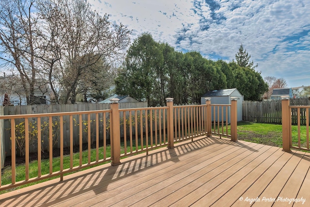 deck featuring a fenced backyard, an outbuilding, a shed, and a lawn