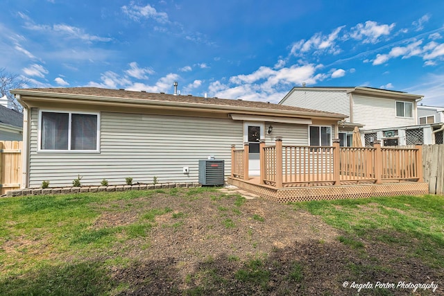 back of property with a lawn, fence, and a deck