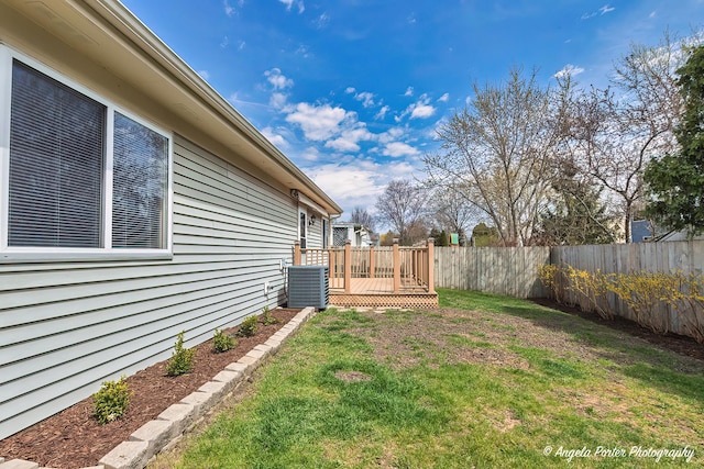 view of yard with central AC, fence, and a deck