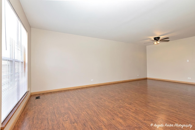 unfurnished room with ceiling fan, baseboards, wood finished floors, and visible vents