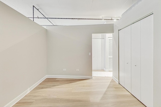 unfurnished bedroom with light wood-type flooring, baseboards, and a closet