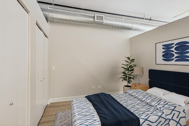 bedroom with baseboards, a closet, visible vents, and light wood-type flooring