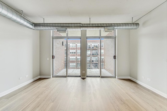spare room with floor to ceiling windows, wood finished floors, and baseboards