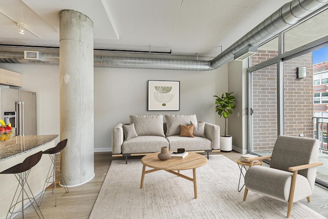 living room with baseboards, light wood finished floors, visible vents, and ornate columns