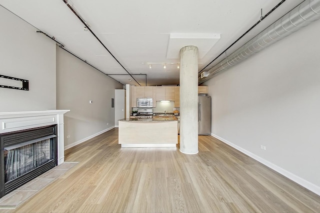 unfurnished living room featuring a fireplace, baseboards, and light wood-style flooring