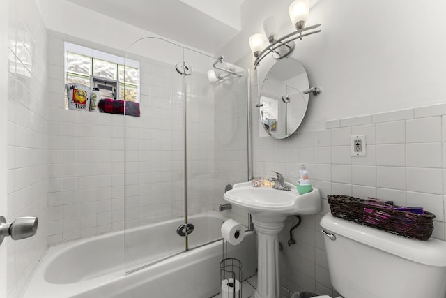 full bathroom with tile walls, toilet, and bath / shower combo with glass door