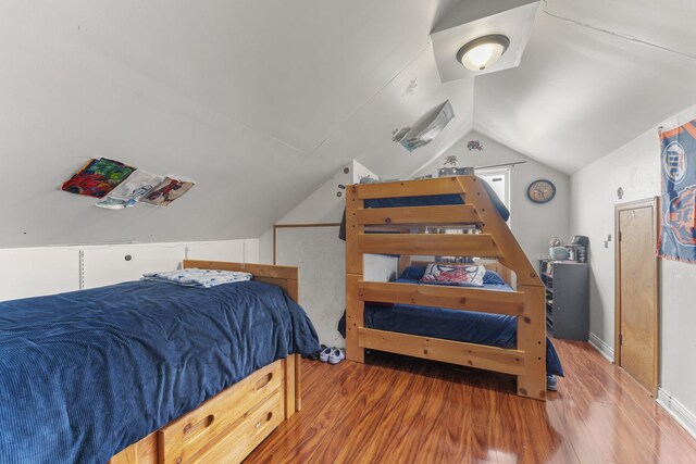 bedroom with wood finished floors and lofted ceiling