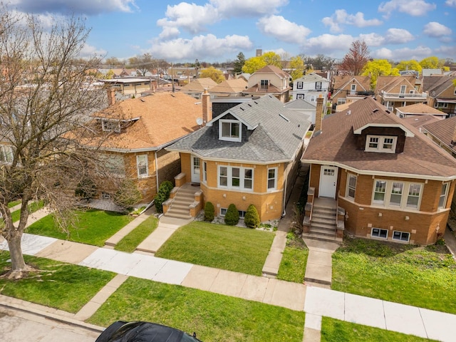 view of front facade featuring a front yard, a residential view, a shingled roof, and a chimney