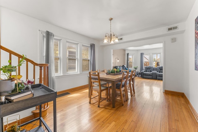 dining area featuring baseboards, visible vents, light wood-style floors, and a notable chandelier