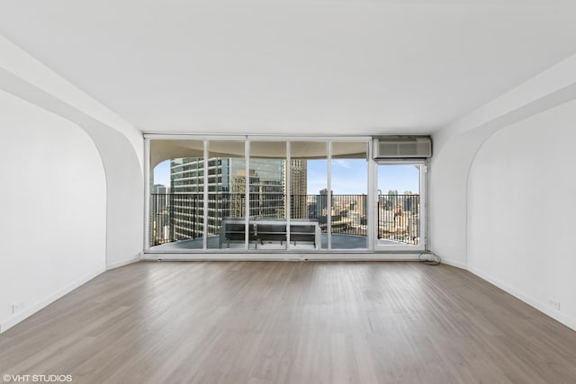 300 N State St Unit 3827, Chicago, IL 60654 - unfurnished room with a wall of windows, wood finished floors, baseboards, and a wall unit AC