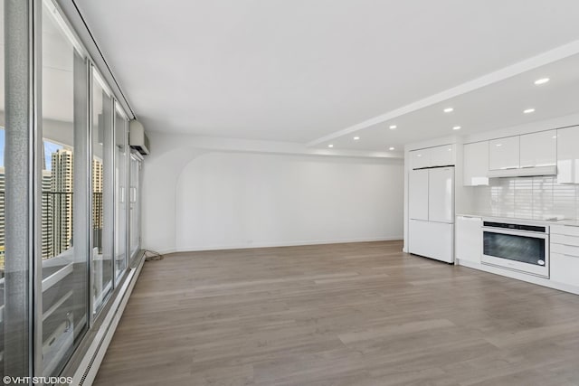 300 N State St Unit 3827, Chicago, IL 60654 - unfurnished living room with light wood-style flooring, a wall unit AC, baseboards, recessed lighting, and baseboard heating