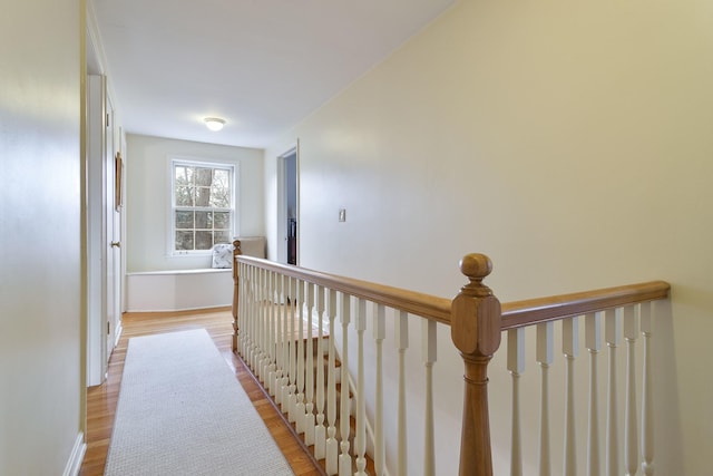 corridor featuring an upstairs landing and light wood-style flooring