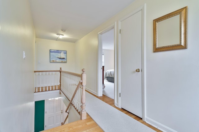 hall featuring an upstairs landing, wood finished floors, and baseboards