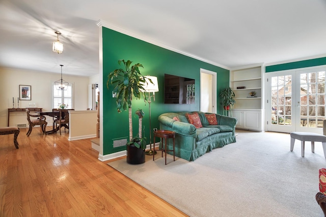 living area with baseboards, ornamental molding, built in features, and wood finished floors