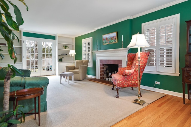 living area with crown molding, baseboards, a fireplace, wood finished floors, and built in shelves