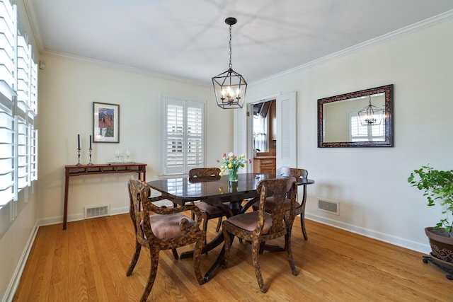 dining space featuring crown molding, visible vents, a chandelier, and light wood-type flooring