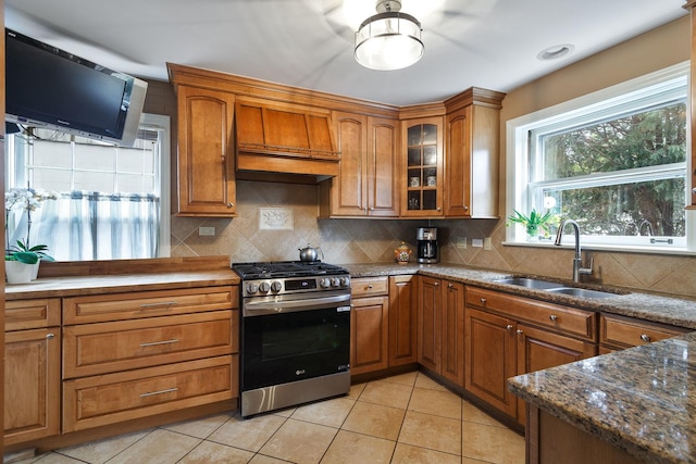 kitchen with gas stove, a sink, custom range hood, and brown cabinets