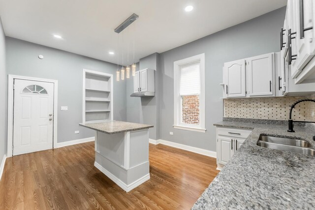 kitchen with light wood-type flooring, baseboards, and a sink