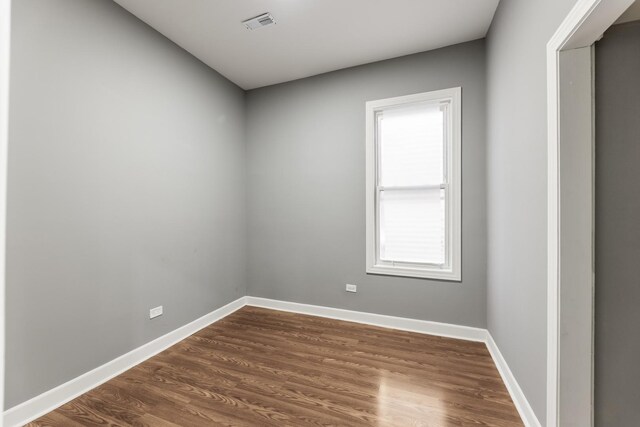 empty room featuring visible vents, baseboards, and dark wood-style flooring