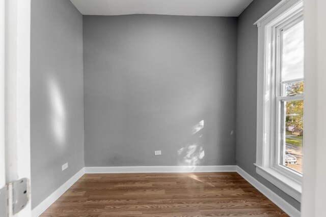 empty room featuring baseboards and dark wood-style floors