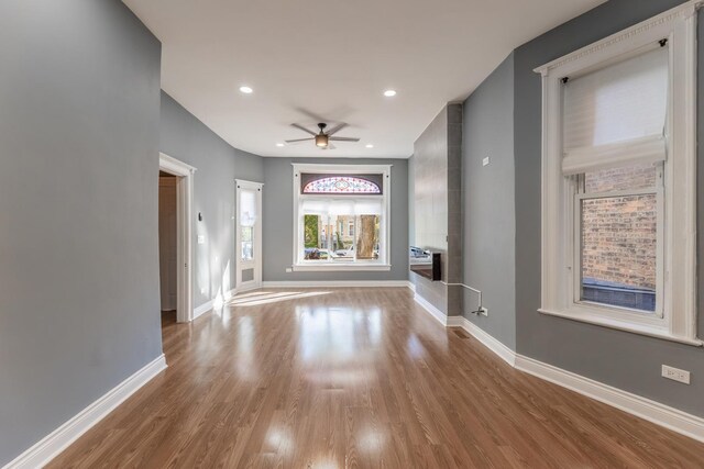 unfurnished living room with wood finished floors, a ceiling fan, baseboards, and recessed lighting