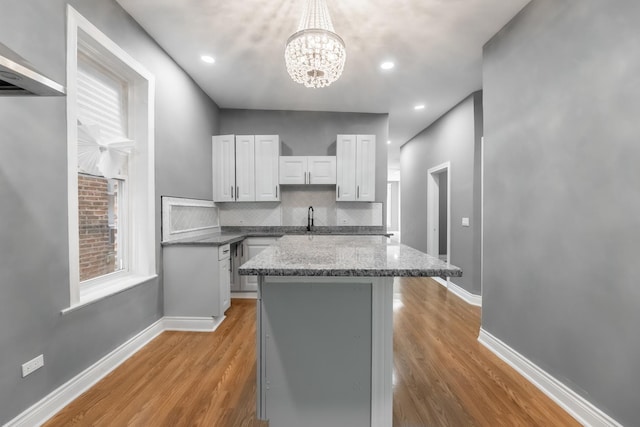 kitchen featuring a sink, light wood-style floors, an inviting chandelier, white cabinetry, and a kitchen island