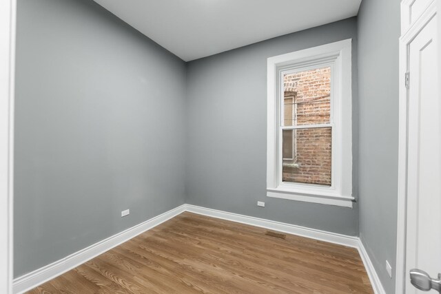 empty room with visible vents, baseboards, and wood finished floors