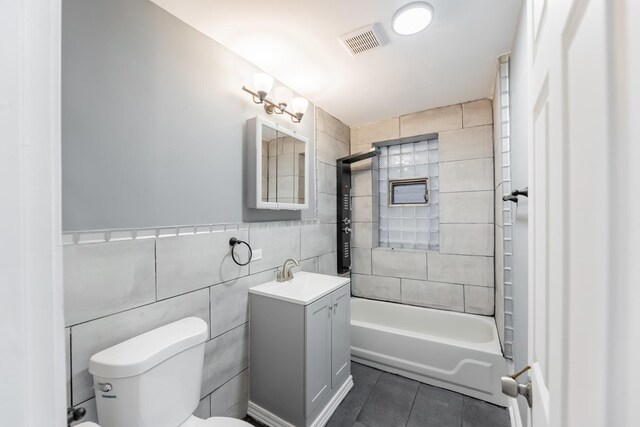 full bathroom with tile patterned floors, vanity, tile walls, toilet, and visible vents
