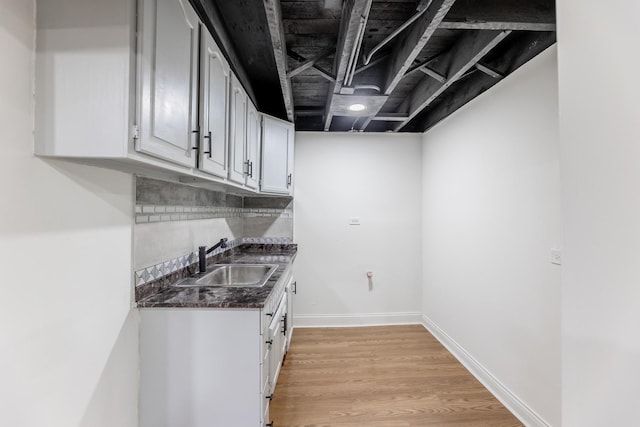 interior space with baseboards, wet bar, a sink, and light wood-style flooring