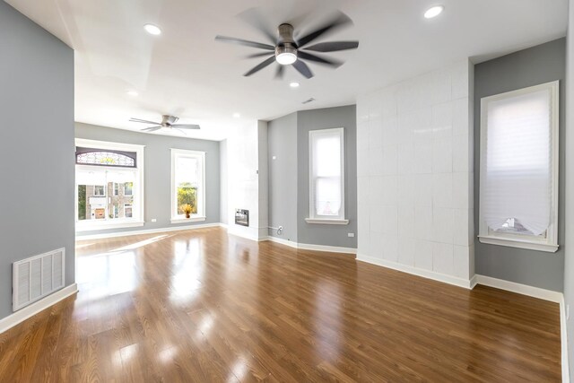 unfurnished living room with ceiling fan, baseboards, wood finished floors, and visible vents