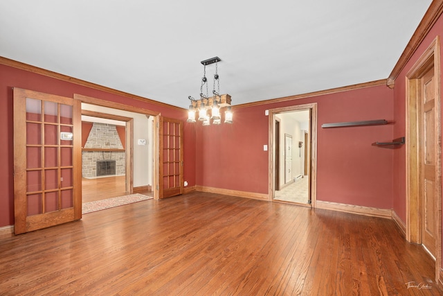 331 E Joliet Hwy, New Lenox, IL 60451 - unfurnished room with hardwood / wood-style floors, baseboards, a fireplace, crown molding, and a chandelier