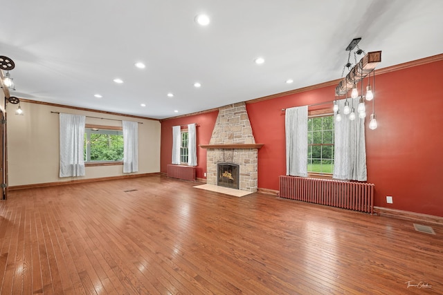 331 E Joliet Hwy, New Lenox, IL 60451 - unfurnished living room with ornamental molding, wood-type flooring, radiator heating unit, baseboards, and a stone fireplace