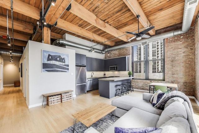 living area featuring wood ceiling, beam ceiling, light wood-type flooring, and brick wall
