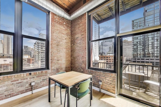 dining space featuring baseboards, a view of city, wood finished floors, and brick wall