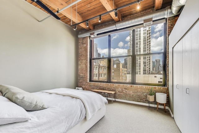 bedroom with brick wall, rail lighting, carpet, wood ceiling, and a city view