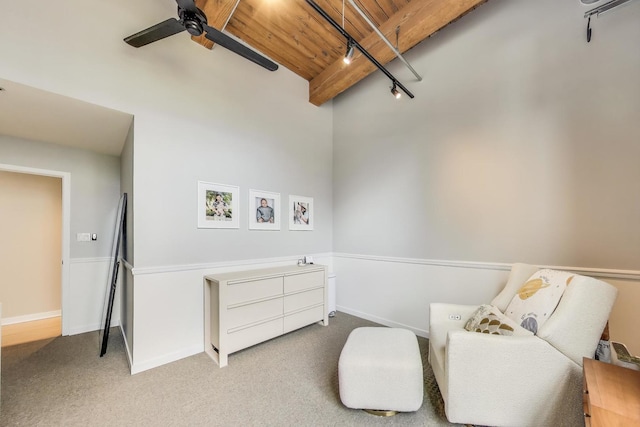 living area featuring carpet floors, a ceiling fan, baseboards, wooden ceiling, and beamed ceiling