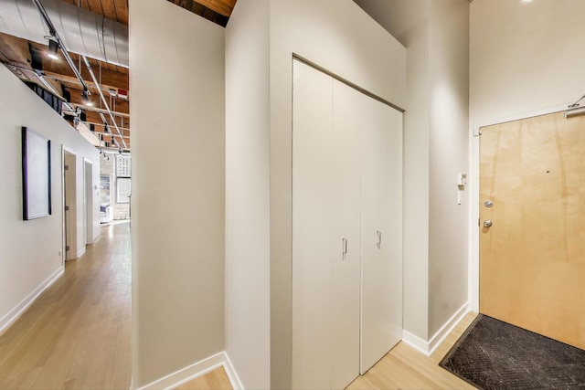 corridor featuring baseboards and light wood finished floors