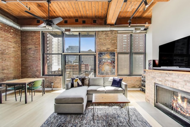 living room featuring wood ceiling, a brick fireplace, wood finished floors, and brick wall