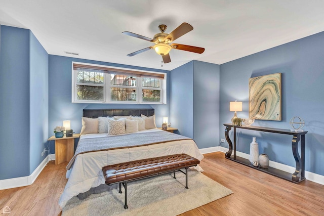 bedroom featuring visible vents, a ceiling fan, baseboards, and wood finished floors