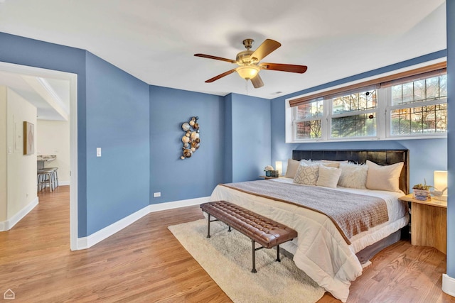 bedroom featuring baseboards, a ceiling fan, and light wood-style flooring